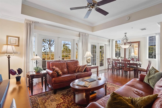 living room with hardwood / wood-style flooring, ornamental molding, a tray ceiling, and french doors