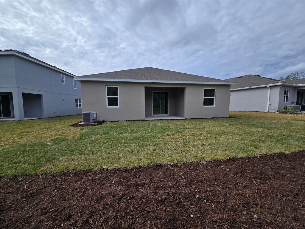 rear view of house featuring cooling unit and a lawn