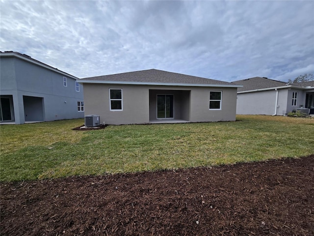 rear view of property featuring roof with shingles, stucco siding, a lawn, and central air condition unit