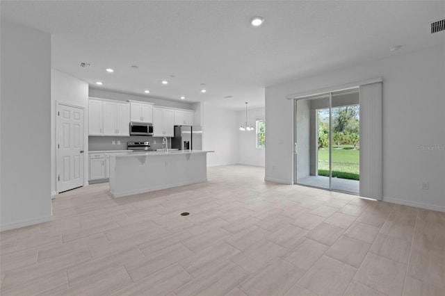 kitchen with stainless steel appliances, visible vents, an inviting chandelier, open floor plan, and white cabinetry