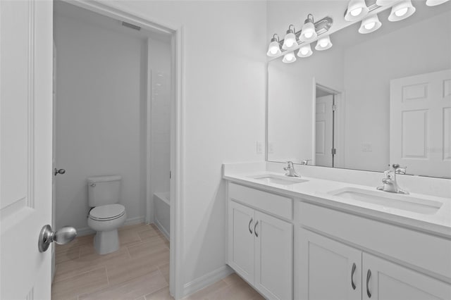 full bath featuring toilet, double vanity, baseboards, and a sink