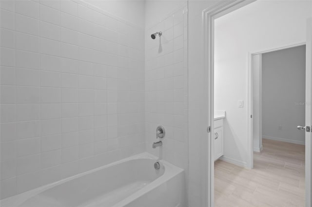 bathroom with shower / bath combination, wood finished floors, vanity, and baseboards