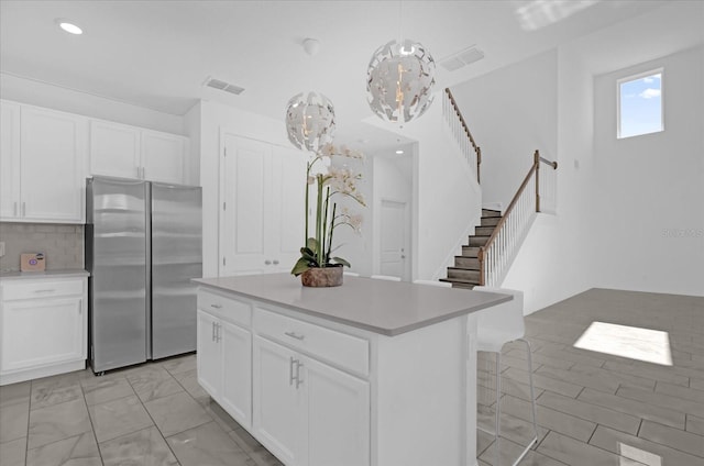 kitchen featuring pendant lighting, a center island, stainless steel fridge, and white cabinetry