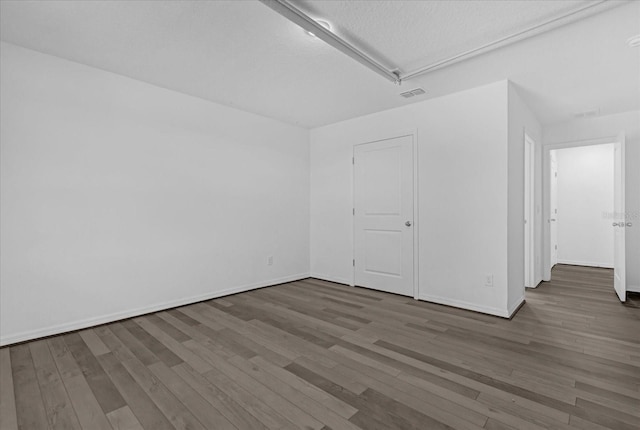 spare room with a textured ceiling and dark wood-type flooring