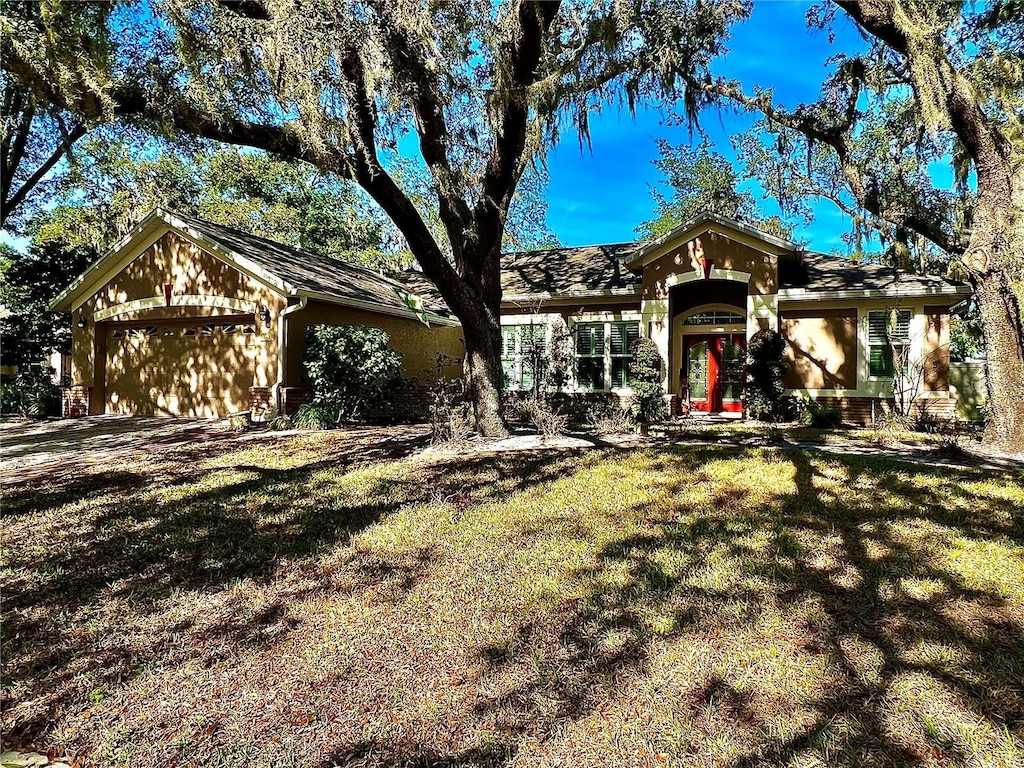 ranch-style home featuring a garage and a front lawn