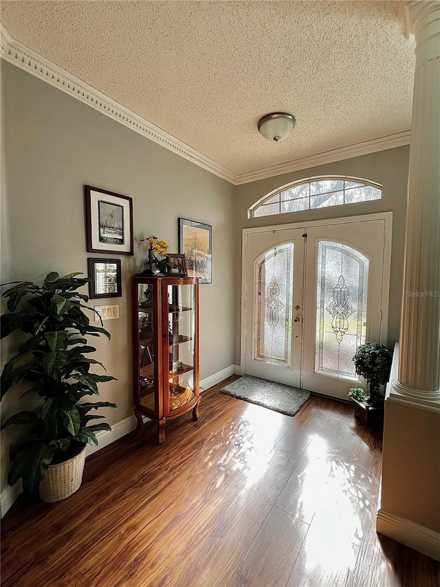 doorway featuring french doors, hardwood / wood-style flooring, ornamental molding, ornate columns, and a textured ceiling