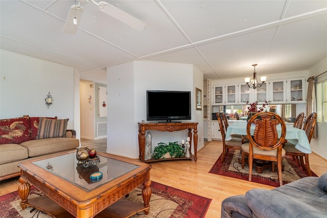 living room featuring a healthy amount of sunlight, ceiling fan with notable chandelier, and light hardwood / wood-style flooring