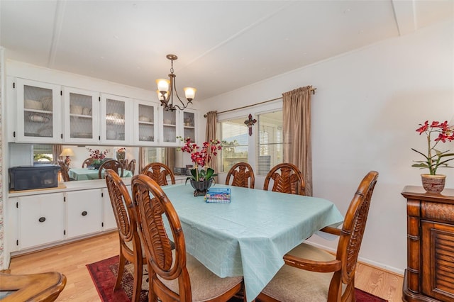 dining space with a wealth of natural light, light hardwood / wood-style flooring, and a notable chandelier