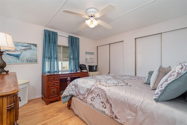 bedroom with ceiling fan, two closets, and light hardwood / wood-style flooring