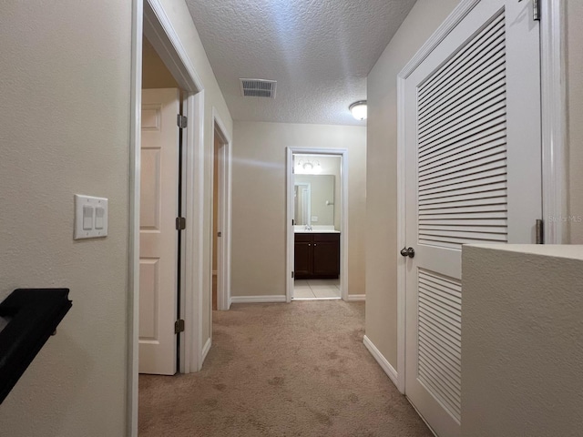 hallway featuring light carpet and a textured ceiling