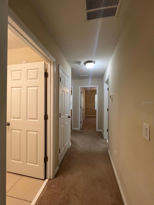 hall featuring light colored carpet and a textured ceiling