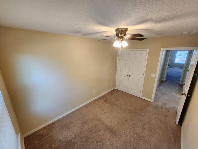 unfurnished bedroom featuring ceiling fan, light colored carpet, a closet, and a textured ceiling