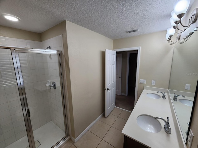 bathroom with a shower with shower door, vanity, a notable chandelier, tile patterned floors, and a textured ceiling