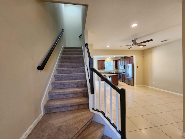 stairway featuring sink, tile patterned floors, and ceiling fan