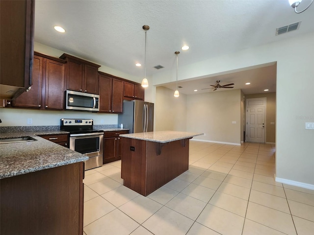 kitchen featuring a kitchen island, appliances with stainless steel finishes, pendant lighting, sink, and dark stone countertops