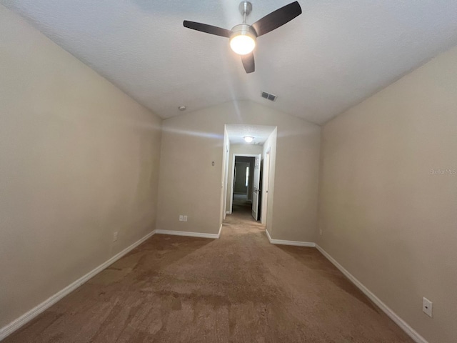 carpeted spare room featuring ceiling fan and vaulted ceiling