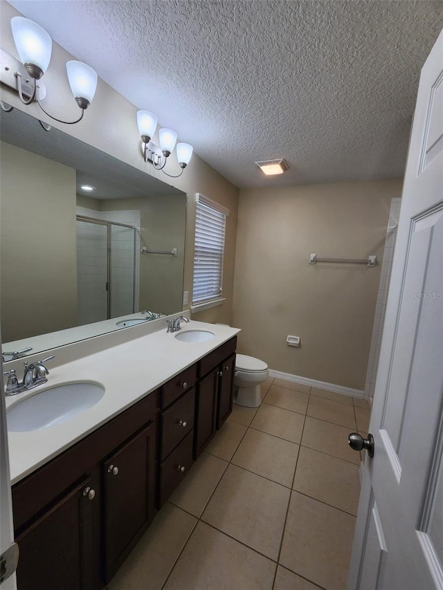 bathroom featuring a shower with door, tile patterned flooring, vanity, a textured ceiling, and toilet