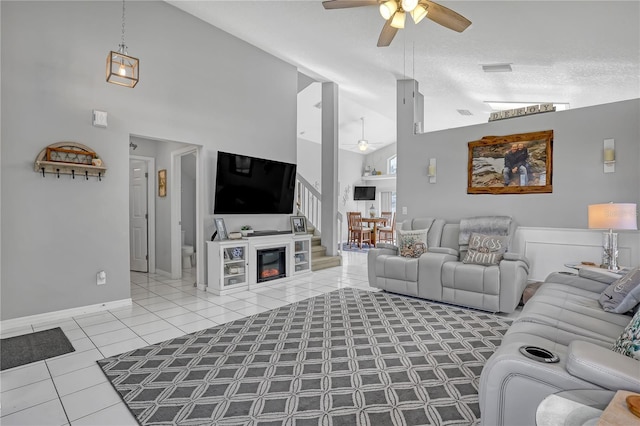 living room with a textured ceiling, ceiling fan, high vaulted ceiling, and tile patterned floors