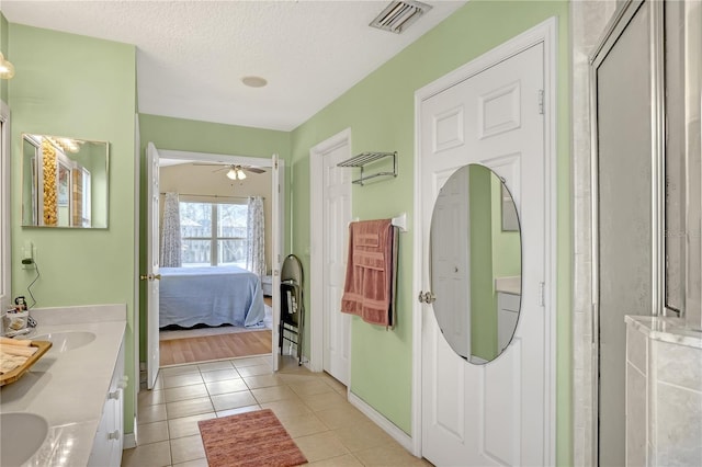 bathroom featuring walk in shower, vanity, tile patterned floors, ceiling fan, and a textured ceiling