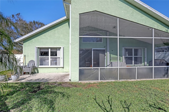 rear view of property with a sunroom, a patio area, and a lawn