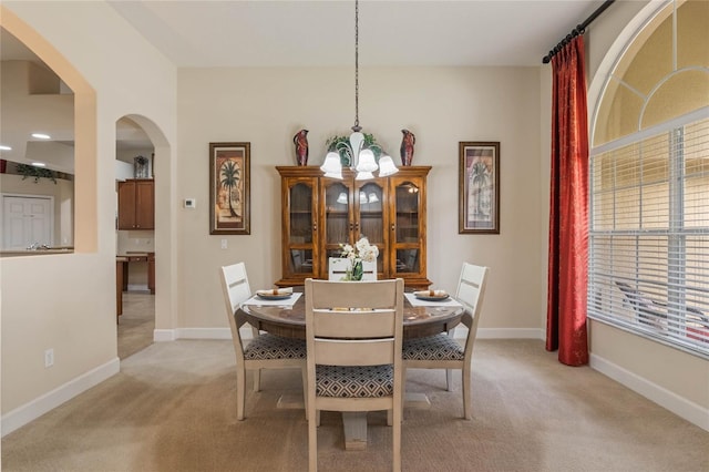 carpeted dining space with a chandelier