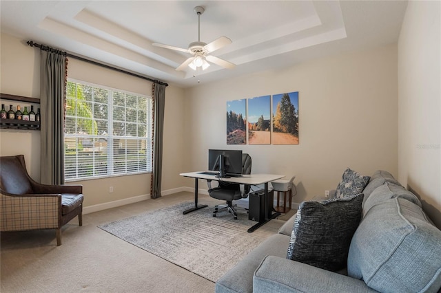 carpeted office featuring ceiling fan and a raised ceiling