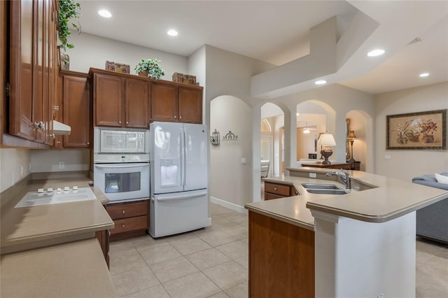 kitchen with sink, white appliances, light tile patterned floors, and an island with sink