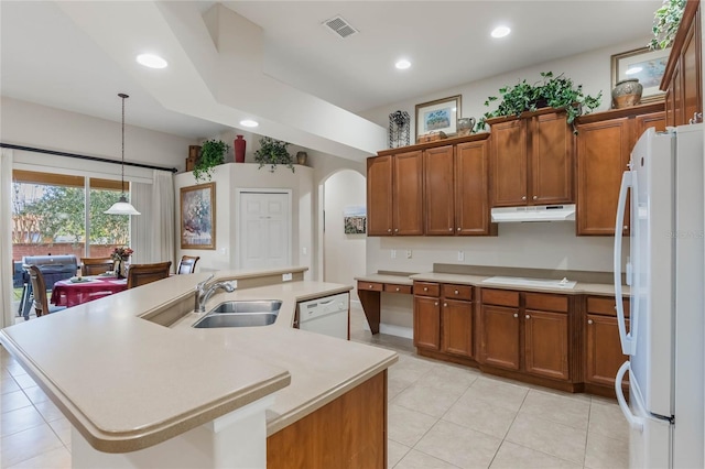 kitchen featuring sink, white appliances, light tile patterned floors, hanging light fixtures, and a kitchen island with sink