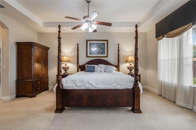 bedroom with a raised ceiling, ceiling fan, and light colored carpet