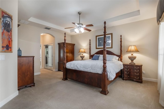 carpeted bedroom featuring ceiling fan and a raised ceiling