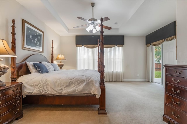 carpeted bedroom featuring access to outside, ceiling fan, and a tray ceiling