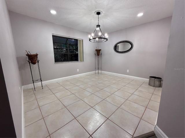 unfurnished dining area featuring a textured ceiling, a chandelier, and light tile patterned flooring