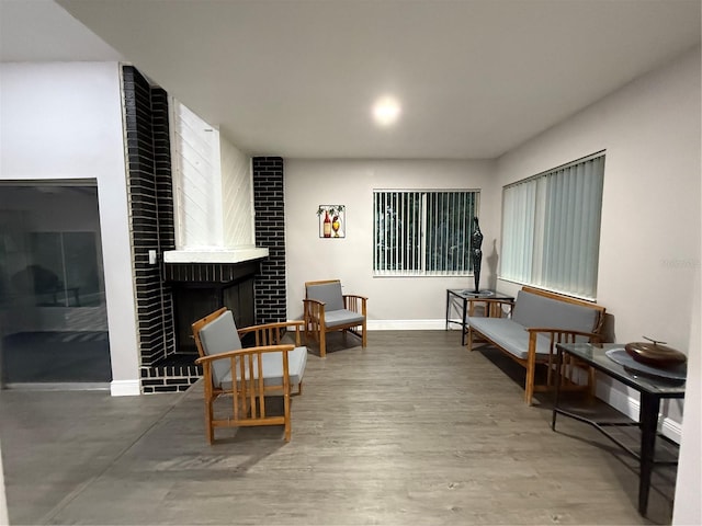 sitting room featuring a brick fireplace and hardwood / wood-style flooring