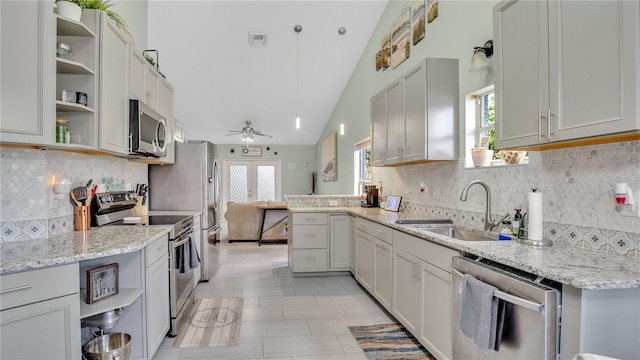 kitchen featuring light stone counters, stainless steel appliances, vaulted ceiling, ceiling fan, and sink