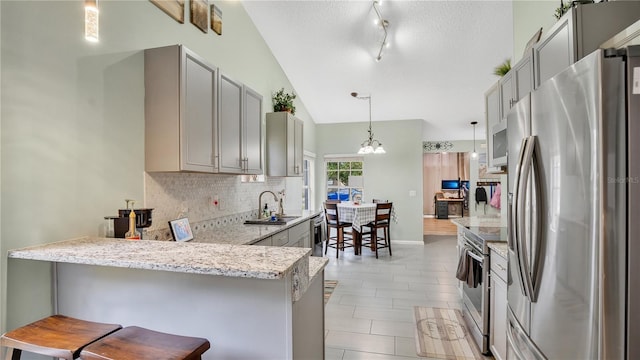 kitchen with kitchen peninsula, pendant lighting, a kitchen bar, gray cabinets, and appliances with stainless steel finishes