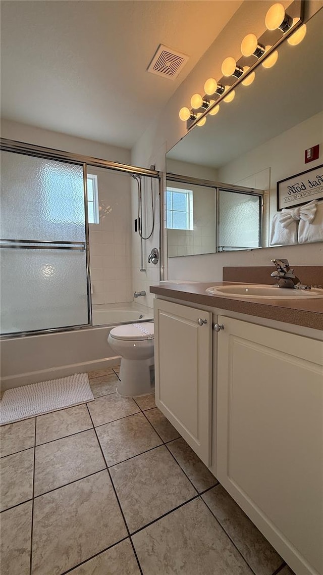 full bathroom featuring vanity, toilet, plenty of natural light, and bath / shower combo with glass door