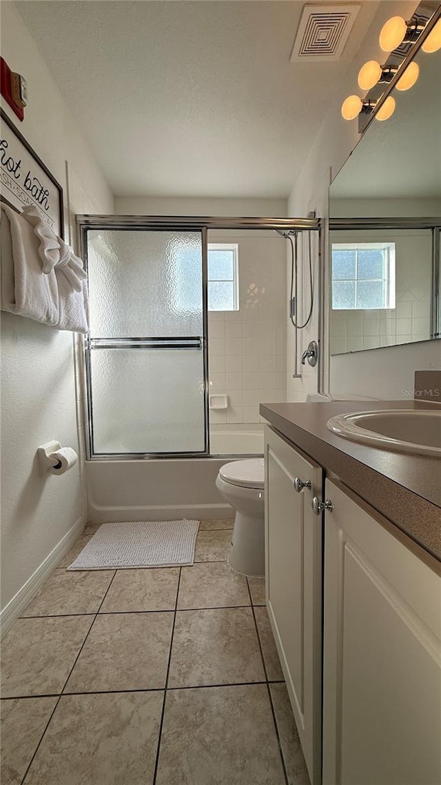 full bathroom featuring toilet, tile patterned flooring, a healthy amount of sunlight, and combined bath / shower with glass door