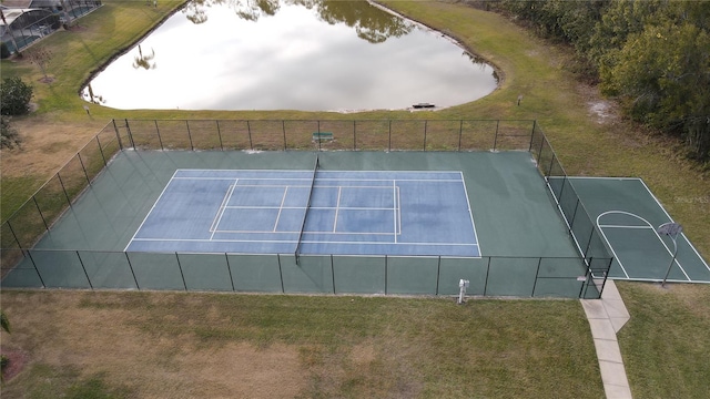 view of sport court with a water view and a lawn