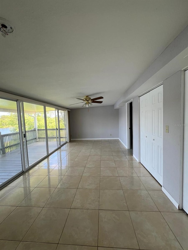 spare room featuring ceiling fan, light tile patterned flooring, and a wall of windows