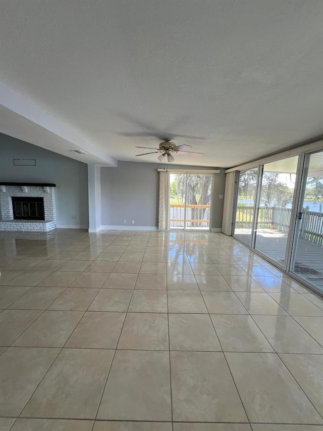 interior space with a fireplace, light tile patterned floors, a textured ceiling, and ceiling fan