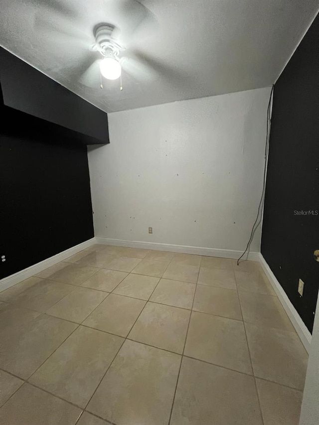 spare room with ceiling fan and light tile patterned floors