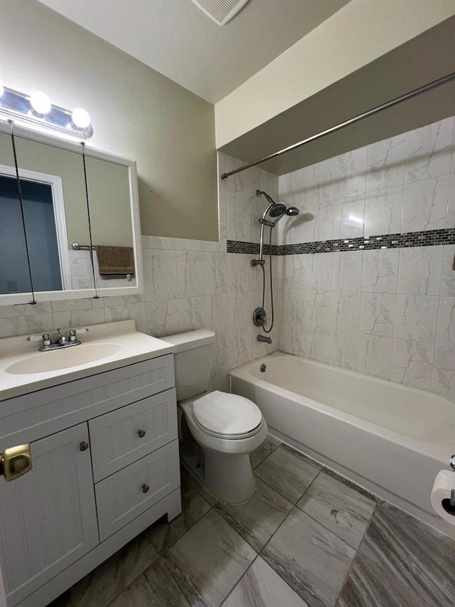 full bathroom featuring vanity, tiled shower / bath combo, tile walls, and toilet