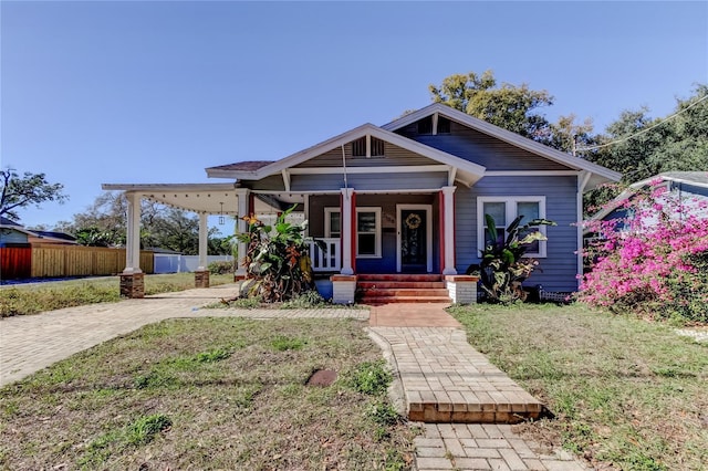 bungalow-style home featuring covered porch and a front lawn