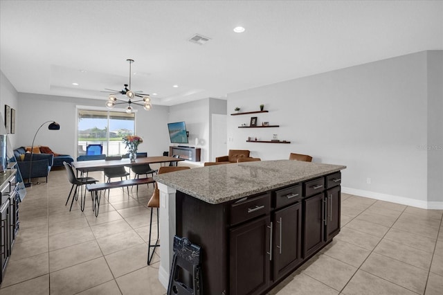 kitchen featuring a kitchen breakfast bar, a kitchen island, a raised ceiling, and light tile patterned floors