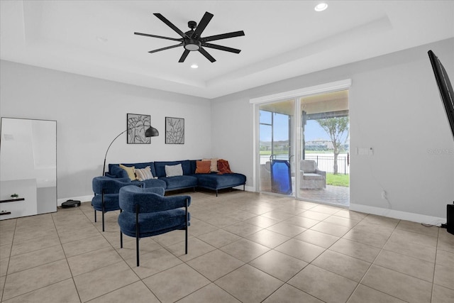 tiled living room with a raised ceiling and ceiling fan