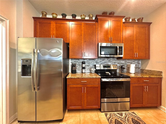 kitchen featuring a textured ceiling, appliances with stainless steel finishes, decorative backsplash, stone countertops, and light tile patterned flooring