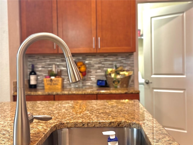 kitchen featuring light stone countertops, backsplash, and sink