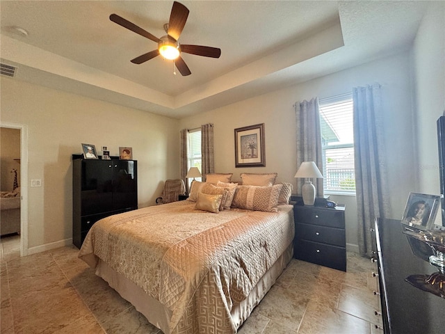 bedroom with ceiling fan and a tray ceiling