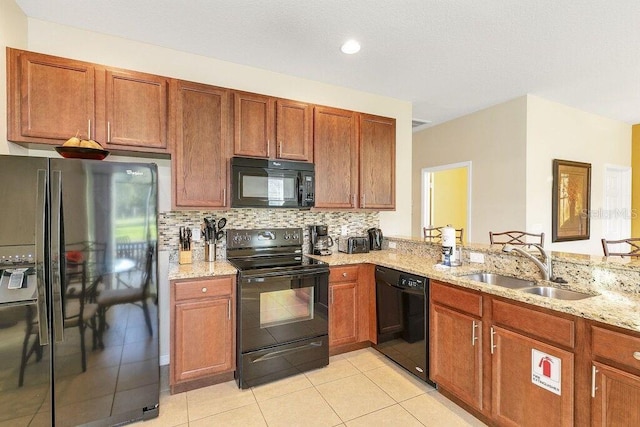 kitchen with light stone countertops, backsplash, sink, black appliances, and light tile patterned flooring