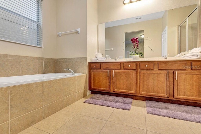 bathroom with tiled tub, tile patterned flooring, and vanity